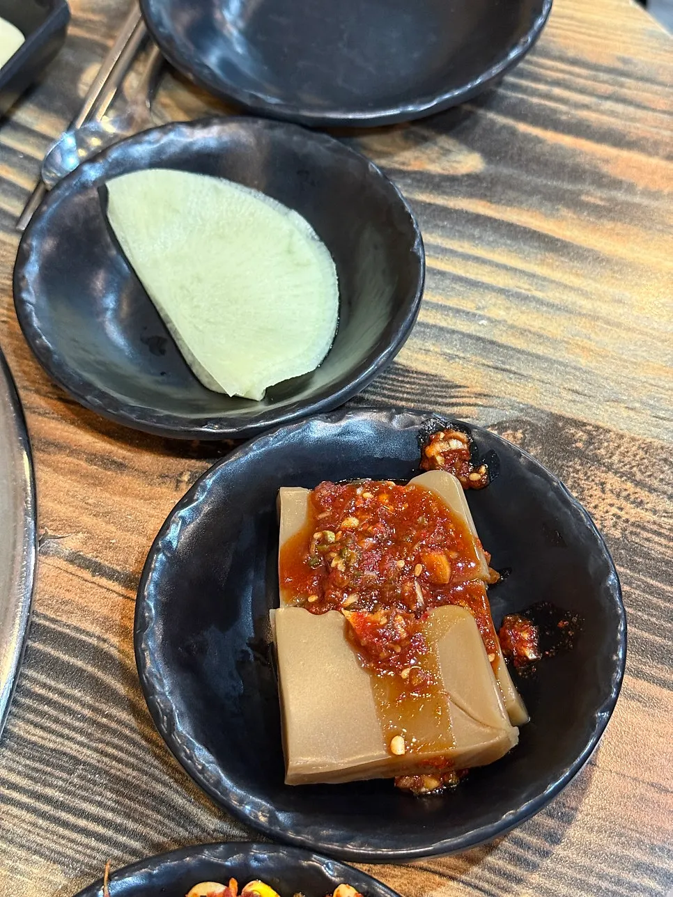 Close-up of green onion kimchi and other pairing side dishes