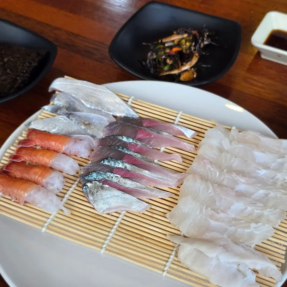 Full table spread with braised cutlassfish, fresh sashimi, and side dishes
