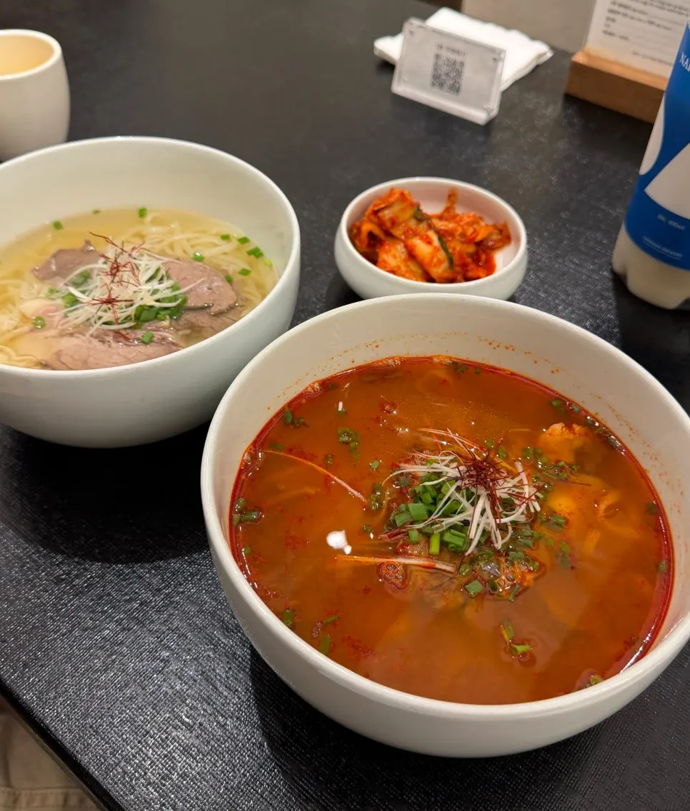 Table setting with two bowls of gomguk and yukgaejang kalguksu