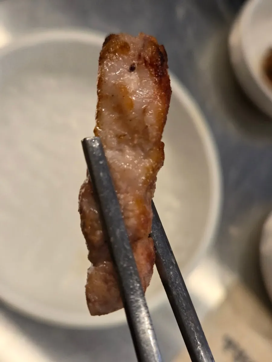 Piece of charcoal-grilled pork belly dipped in garlic sauce