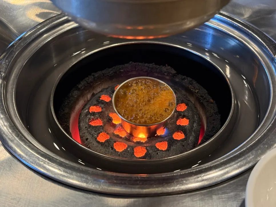 Myeolchi-jeot sauce simmering over the charcoal briquettes