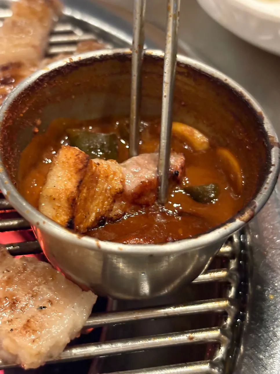 Pork belly grilling over the charcoal grate