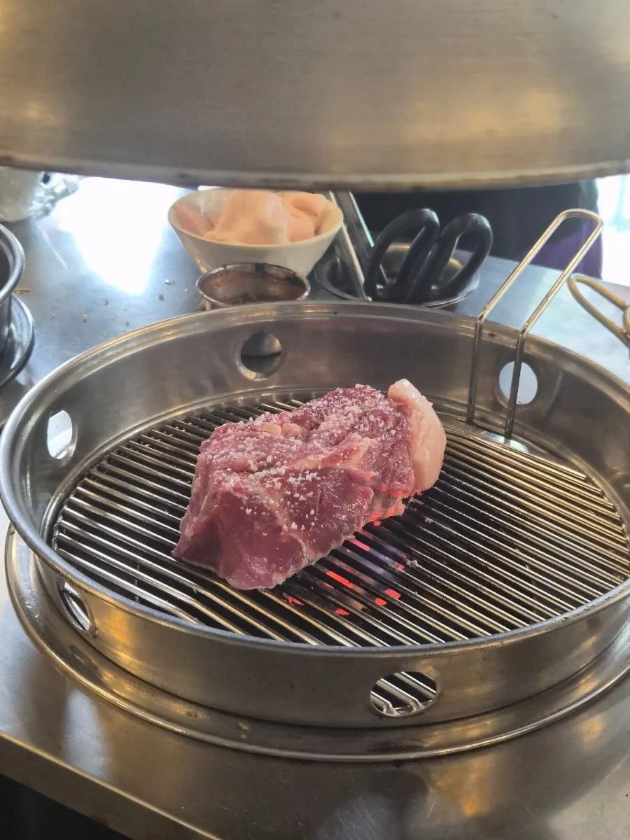 Pork being pre-grilled over high charcoal heat