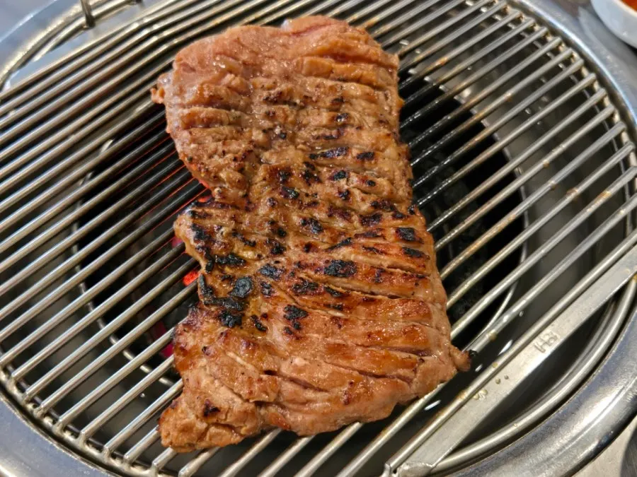 Pre-seared meat placed on top of the charcoal