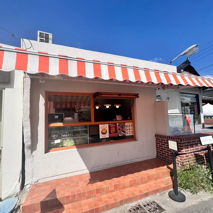 Fachada de Tareudang con cartel naranja y dibujo de mochi