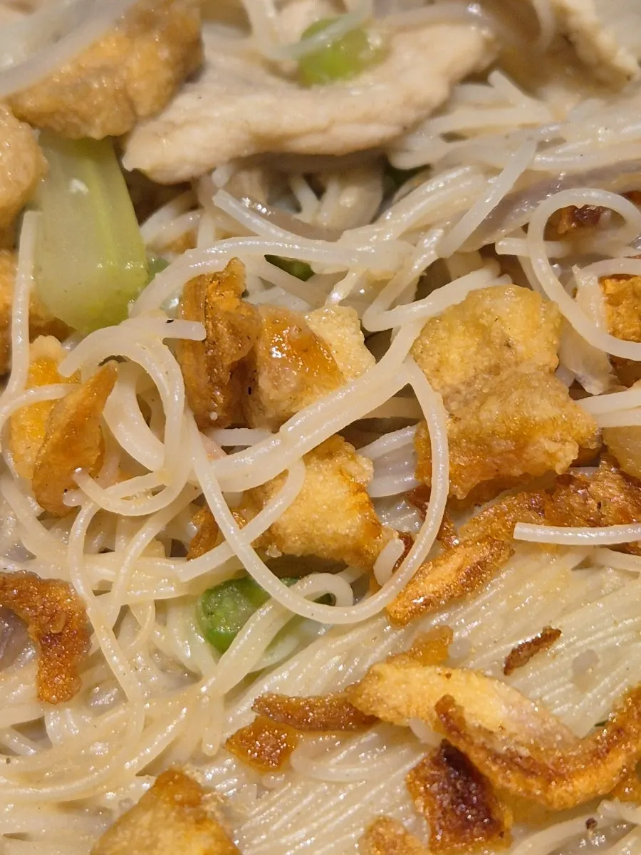 Thin noodles soaking in a shallow pool of shrimp broth