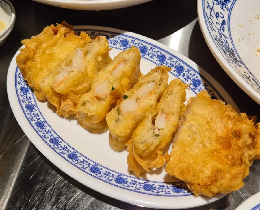 A plate of fried shrimp rolls served with sauce