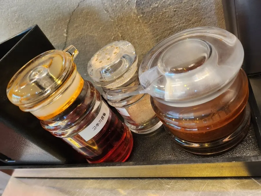 Table setting with chili oil, pepper, and sambal sauce