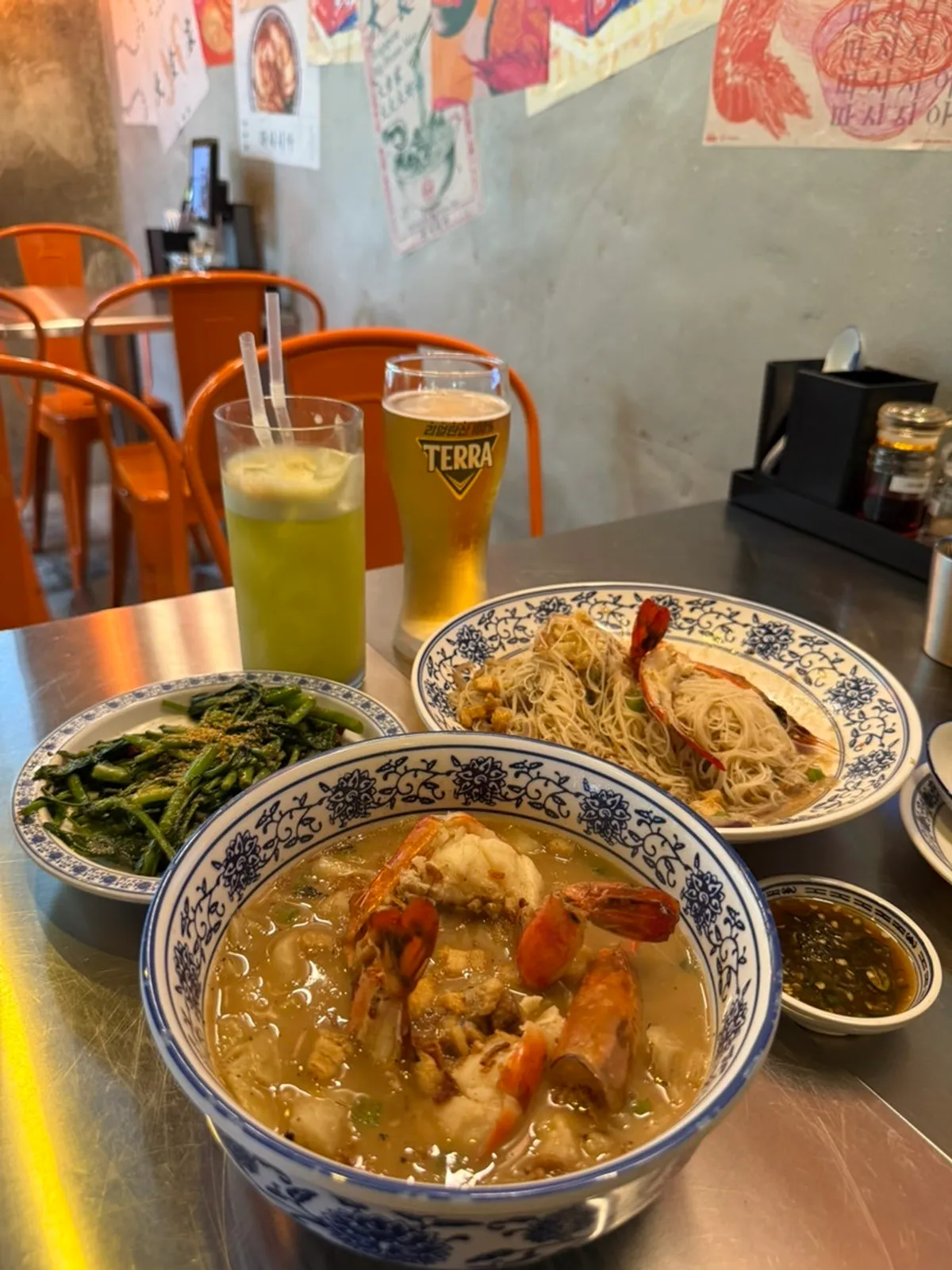 Full table spread of shrimp broth fried noodles, shrimp gukbap, and stir-fried kang kong