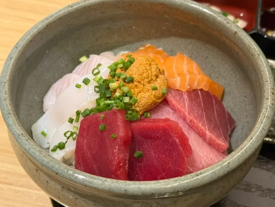 A bite of kaisendon with rice and sashimi wrapped in seaweed