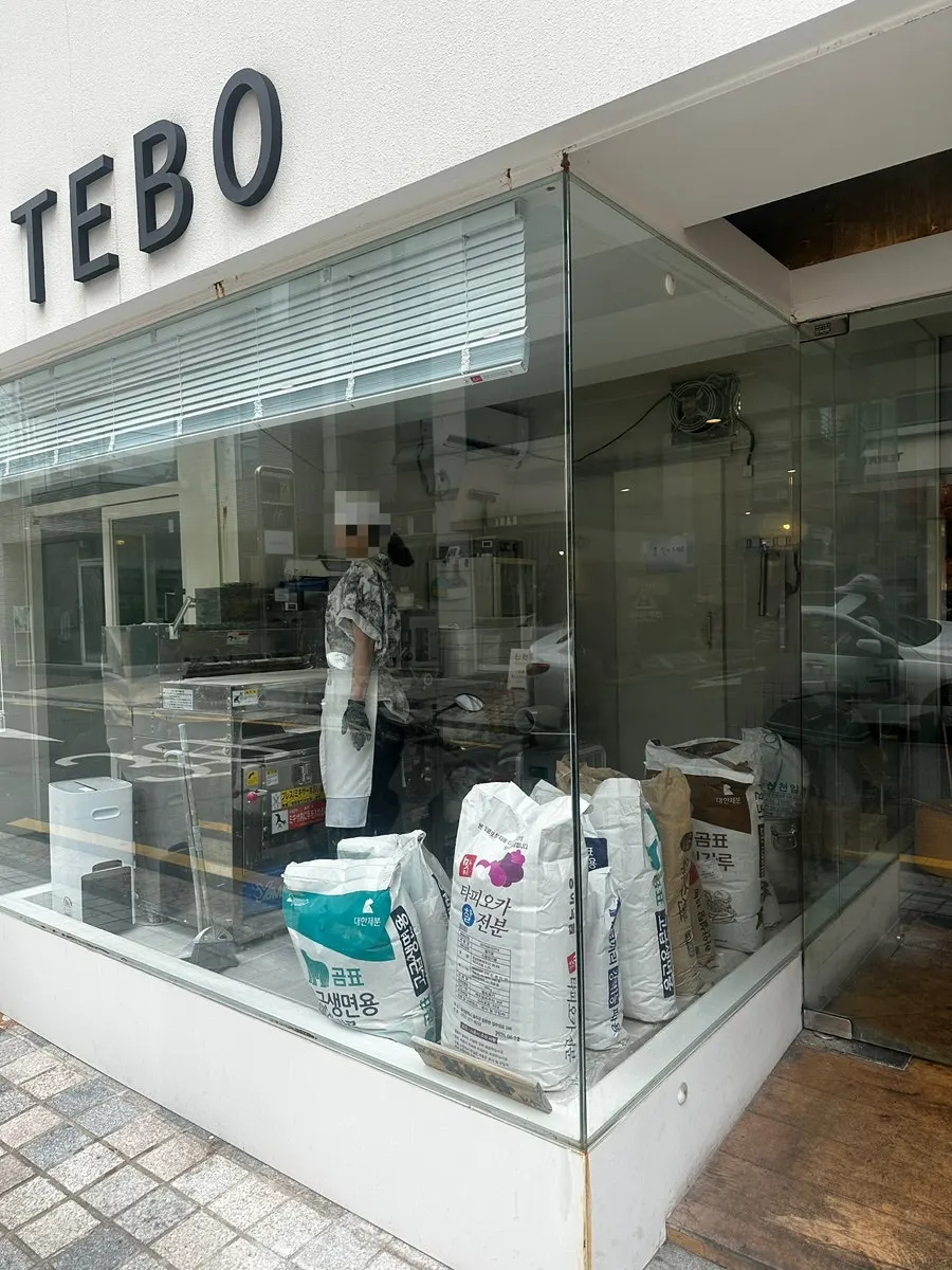 Noodle-making machine and flour bags visible through the glass window