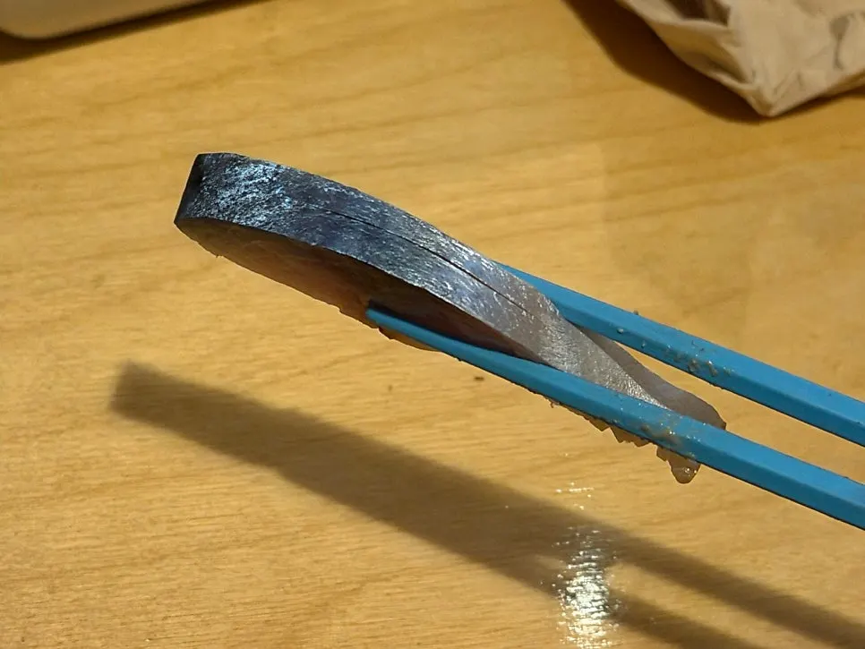 A piece of aged sashimi dipped in soy sauce