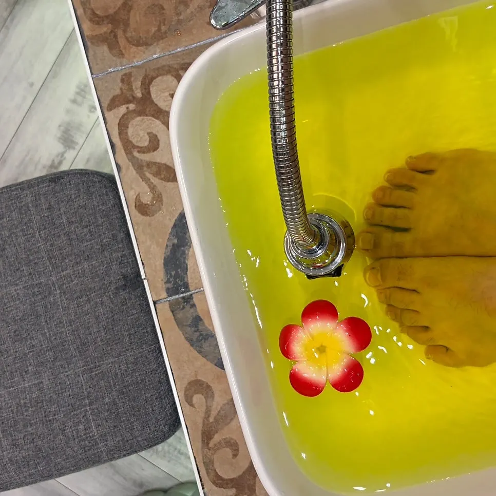 Feet soaking in yellow-tinted herbal foot bath water