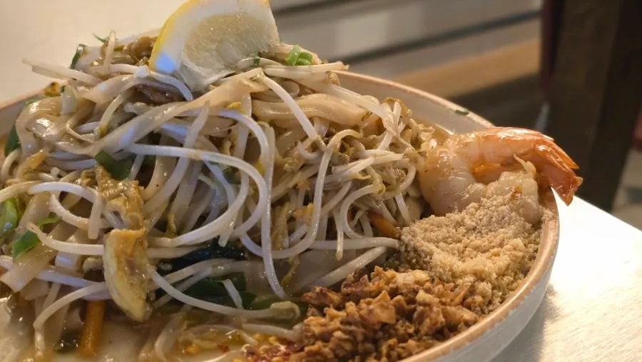 A plate of pad thai with cilantro served on the side