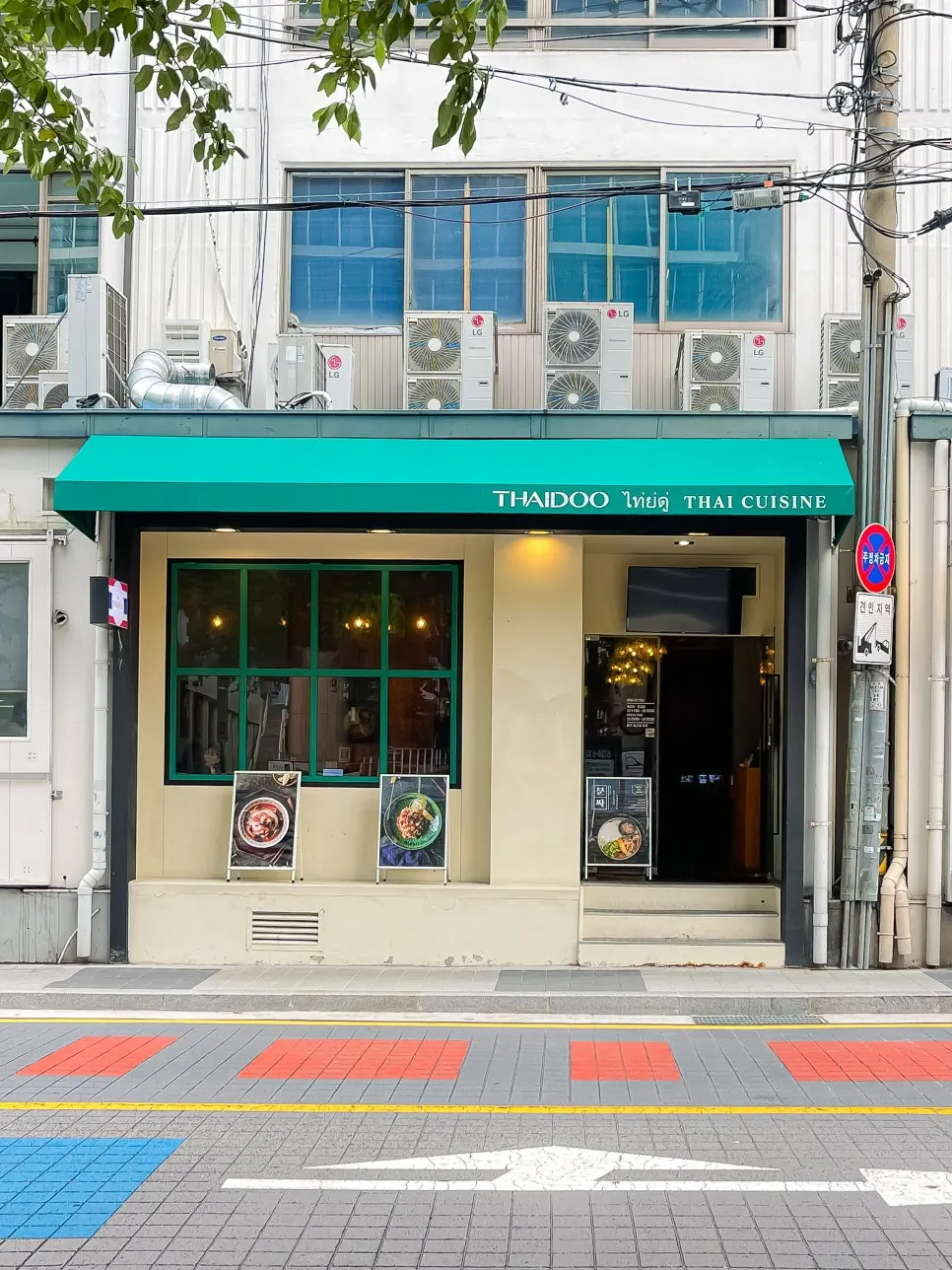 아이보리 벽면에 초록색 어닝이 있는 타이두 외관