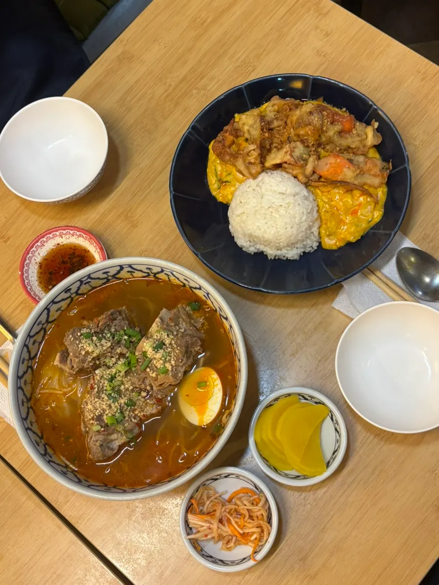 A table spread of gamjatang pho and pad pong curry at Thanon55