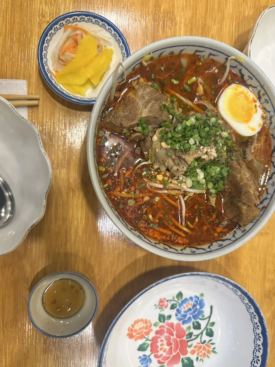 Pork bone rice noodle soup topped with three chunks of meat and an egg