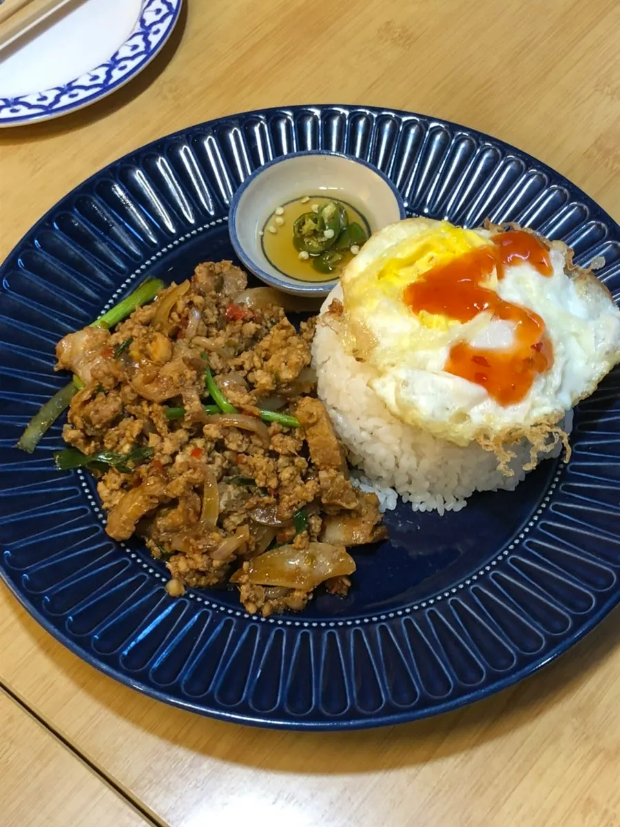 A plate of pad kra pao moo sap topped with egg