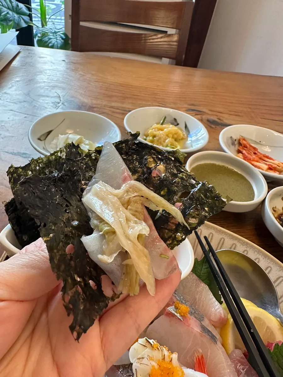 A bite of sashimi rice bowl topped with dried laver and aged kimchi