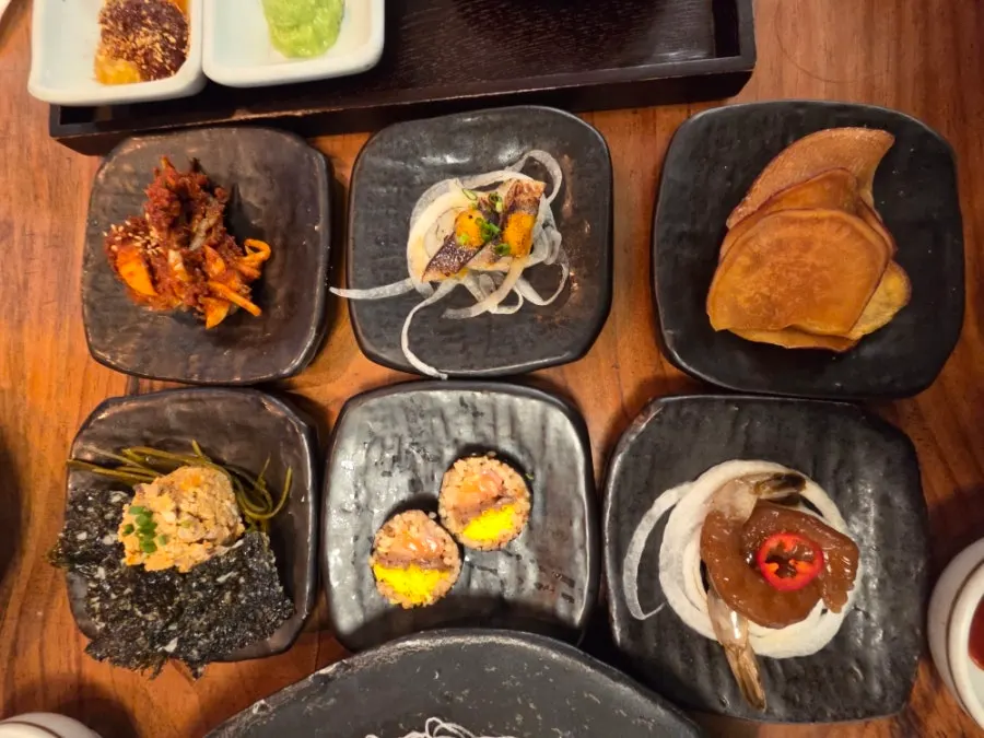 Side dishes of tataki, sweet potato chips, futomaki, and soy-marinated shrimp