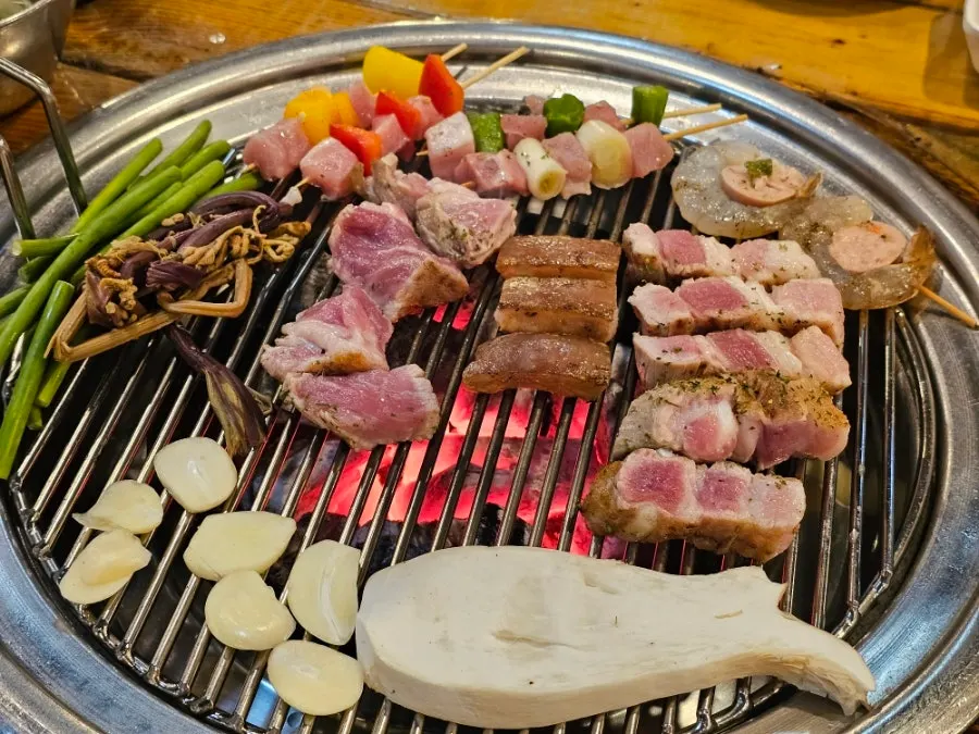 Pre-grilled meat on the grill with skewers set aside in residual heat