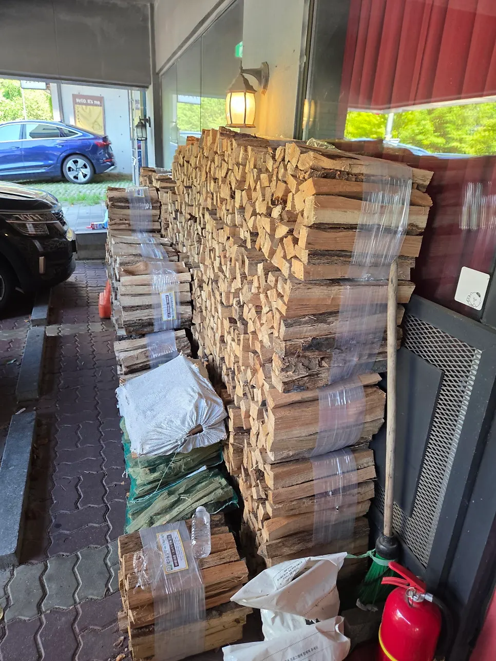 Restaurant entrance with a red door and stacked firewood for the wood-fired oven