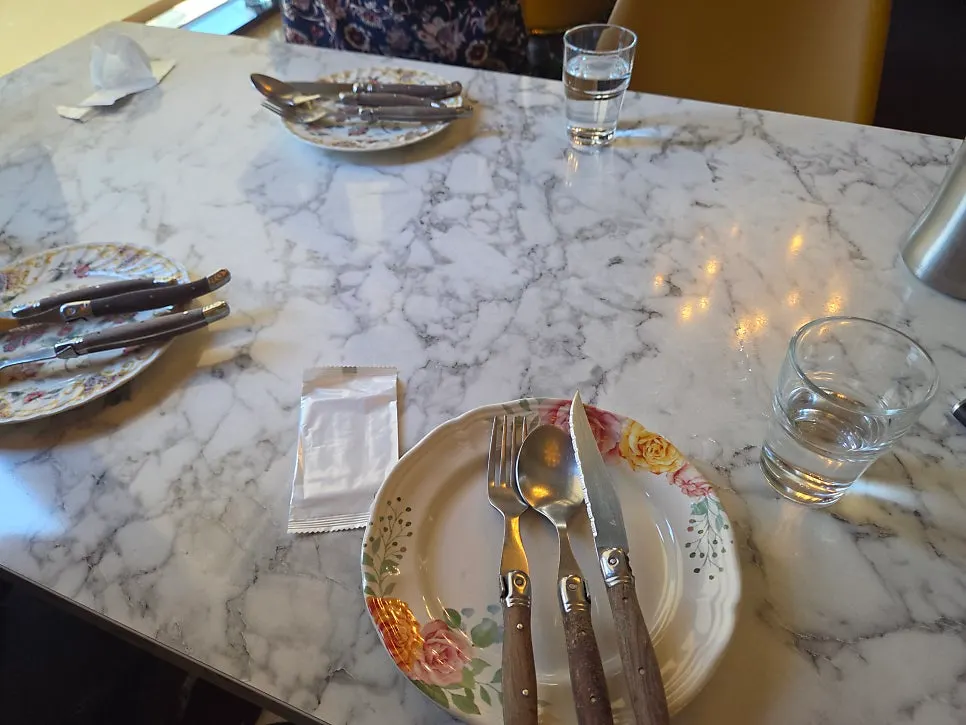 Marble-look table set with flower-patterned plates and wood-handled cutlery