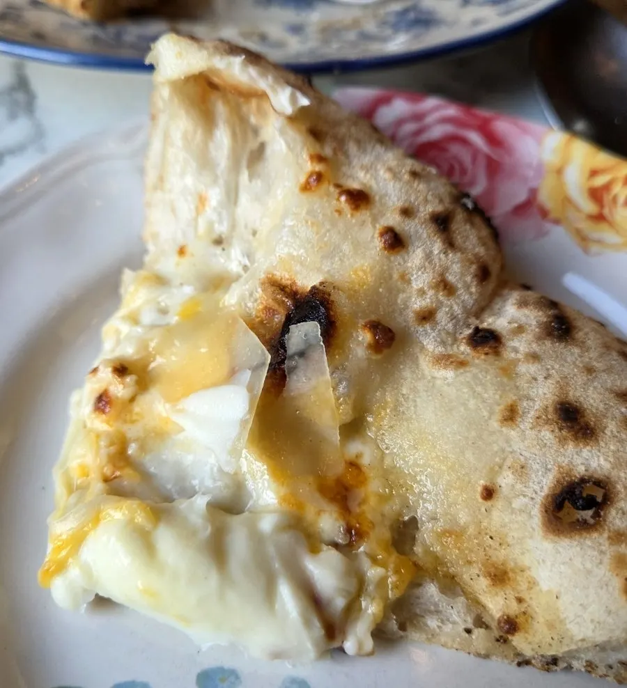 Cross-section of pizza with hamón and layered cheeses