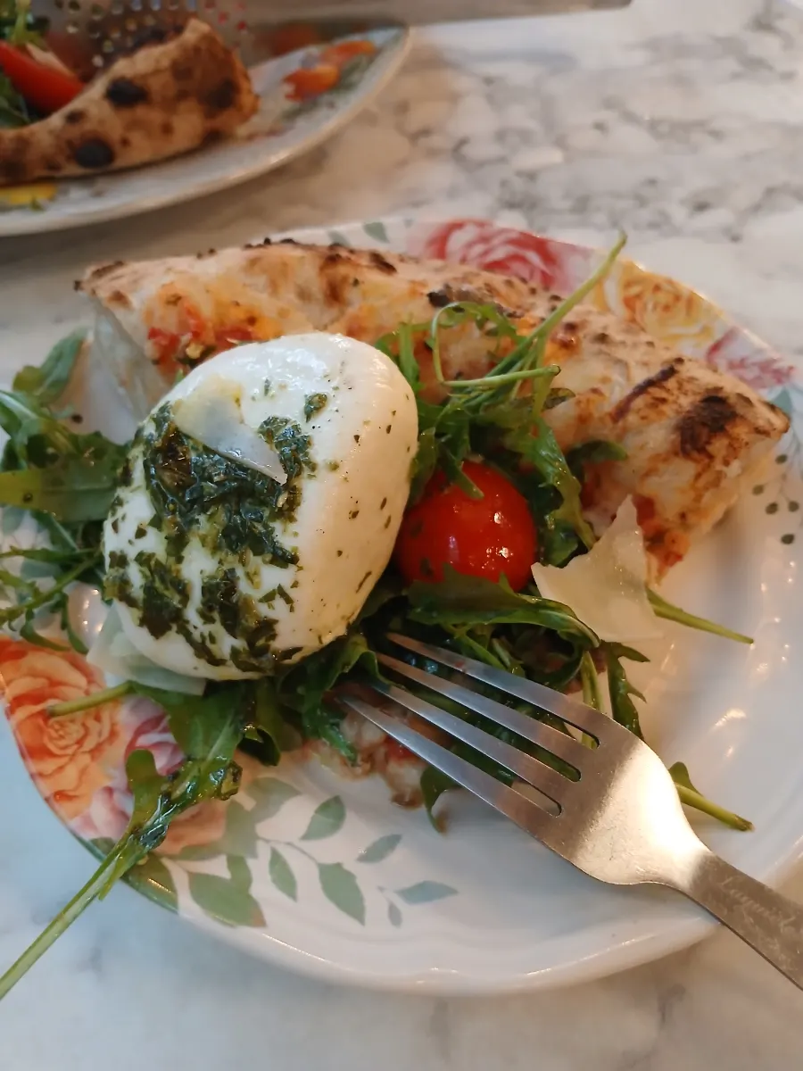 Wood-fired pizza combining basil pesto, rocket, and burrata cheese