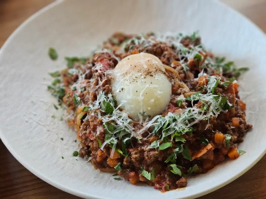 Beef ragu pasta topped with a poached egg