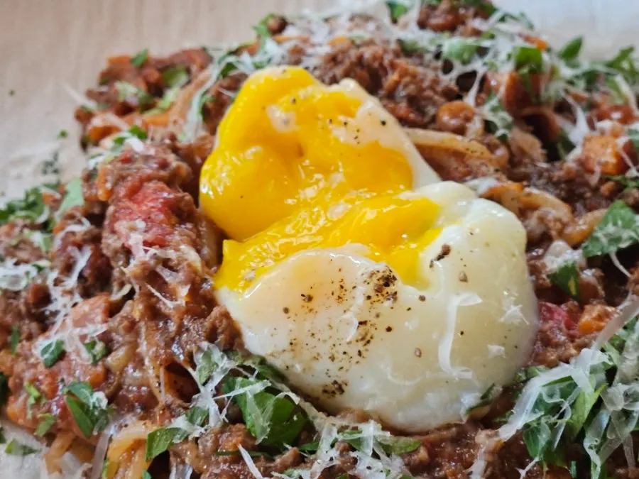Ragu pasta sauce with the poached egg broken open