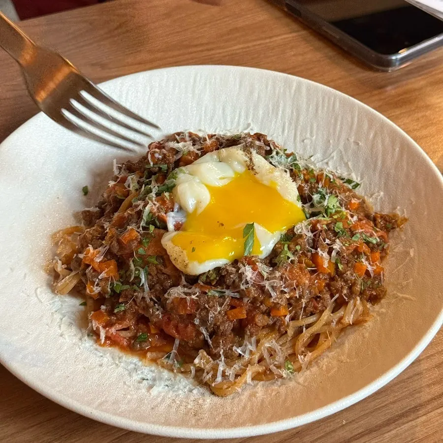Poached egg yolk broken open on the pasta