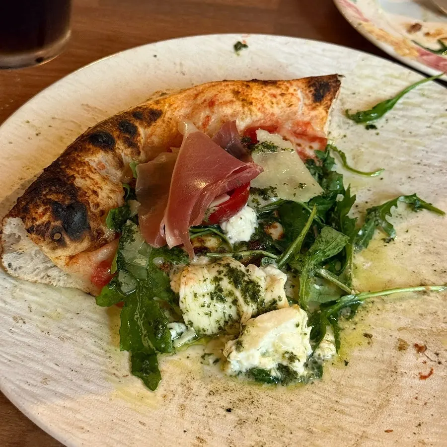 Pizza slice topped with hamon, tomato, and basil