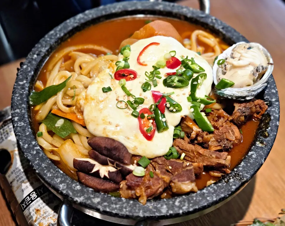 A pot of spicy braised pork ribs topped with cheese