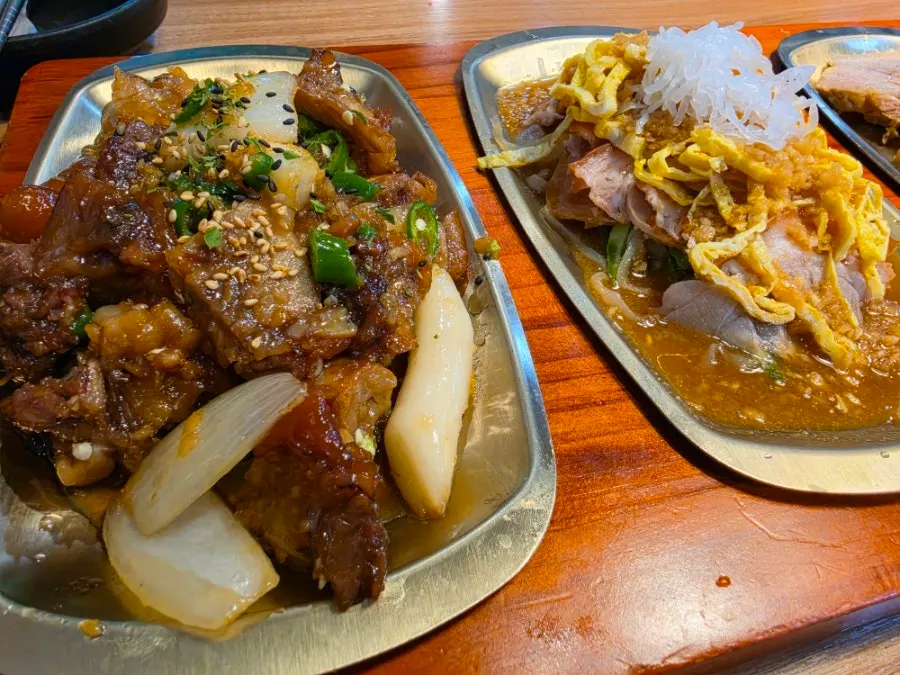 Soy garlic jokbal served with rice cake sticks and onions