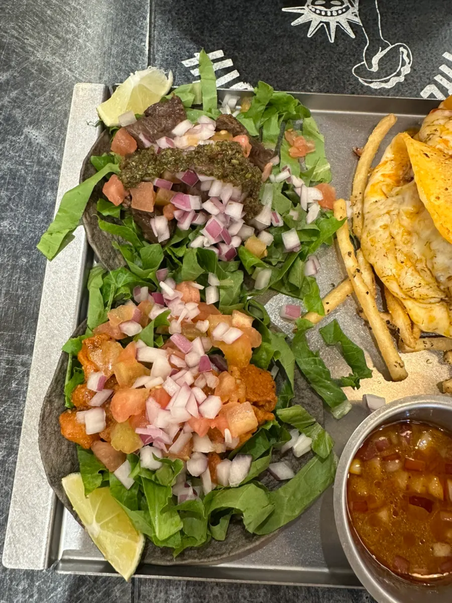 A single taco topped with vegetables, tomato, and onion