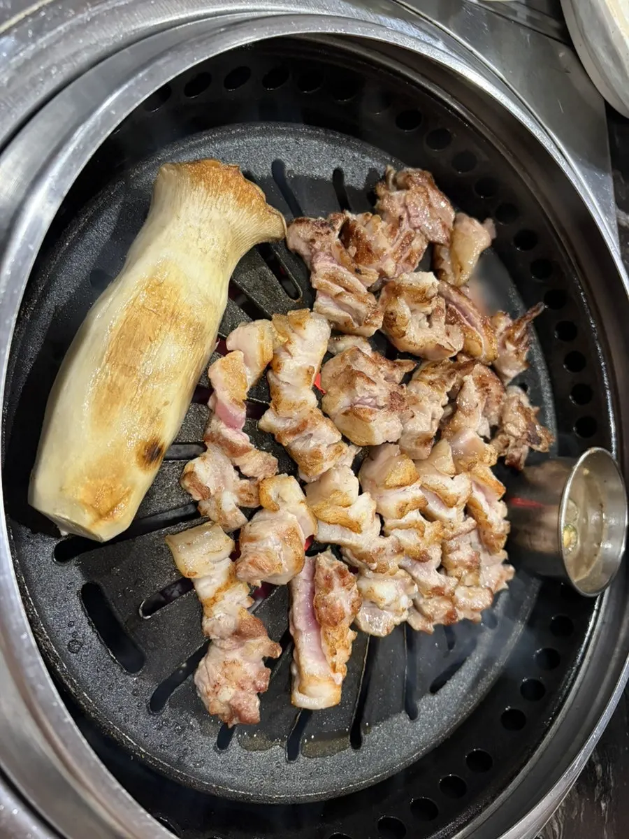 Whole mushrooms and meat grilling together on the pan
