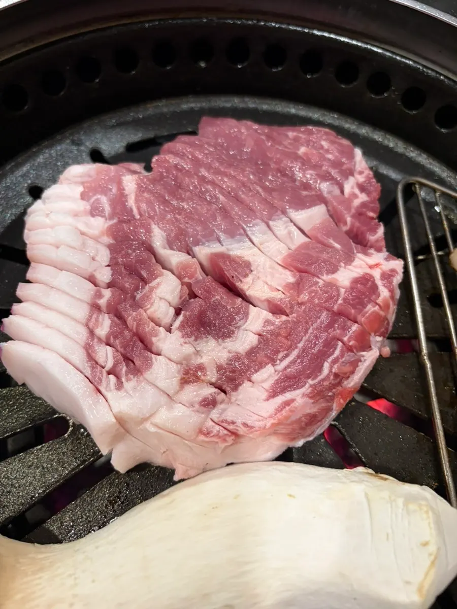 A large chunk of black pork neck on the grill