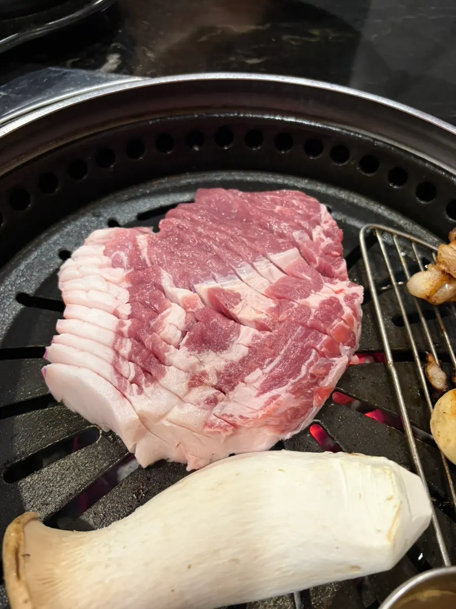 Thick black pork neck being grilled