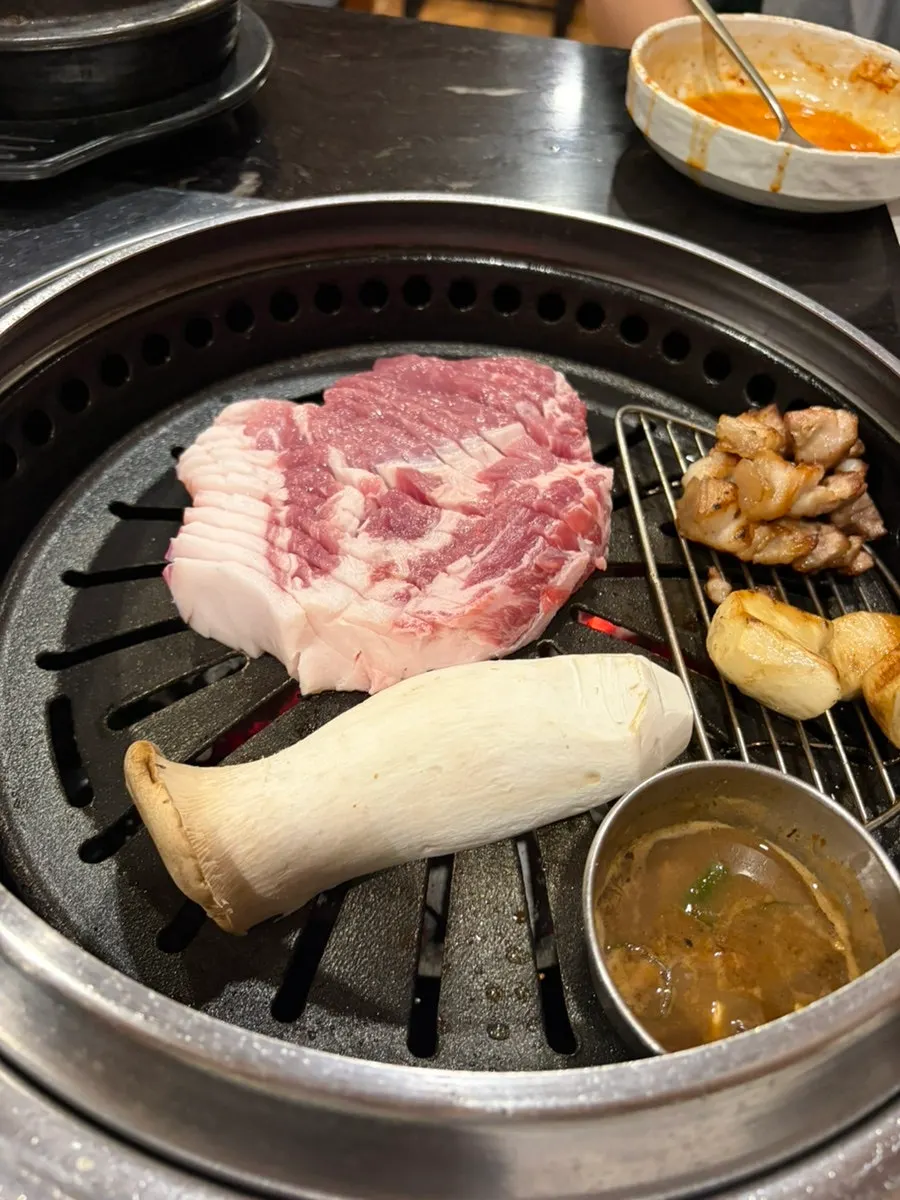 A staff member grilling black pork neck on the pan