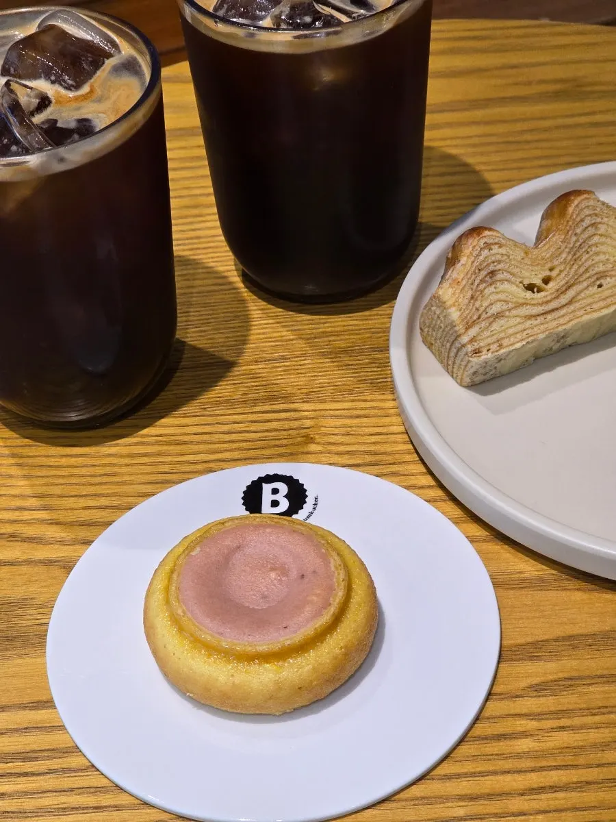 A bite taken from the baumkuchen alongside an iced americano