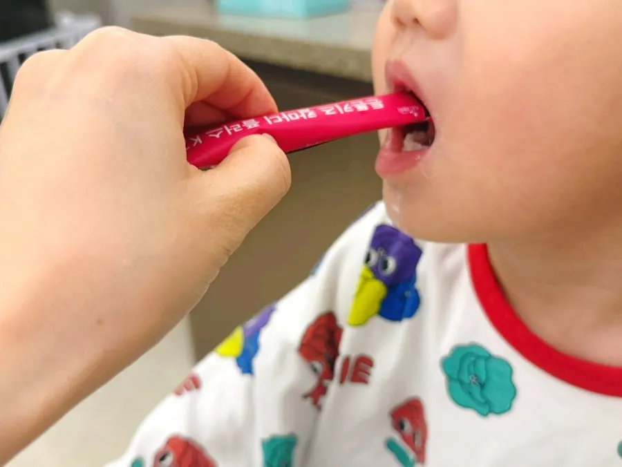 A child eating strawberry-flavored Cal-Mag-D without resistance