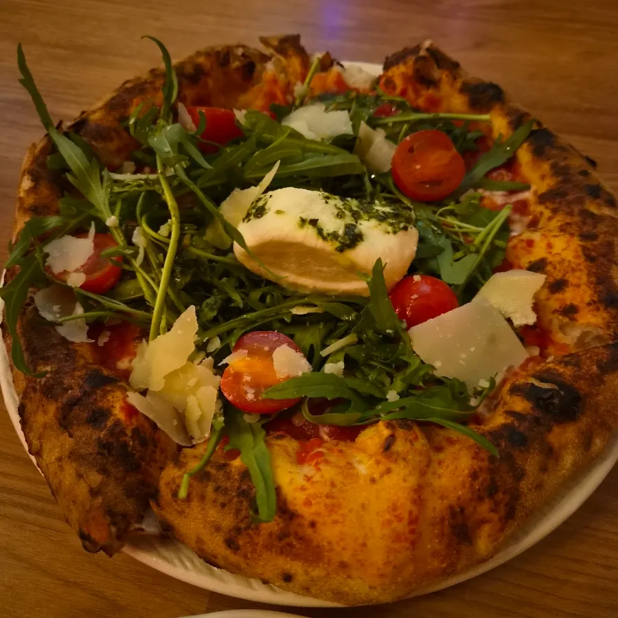Wood-fired arugula burrata pizza with a puffed-up crust edge