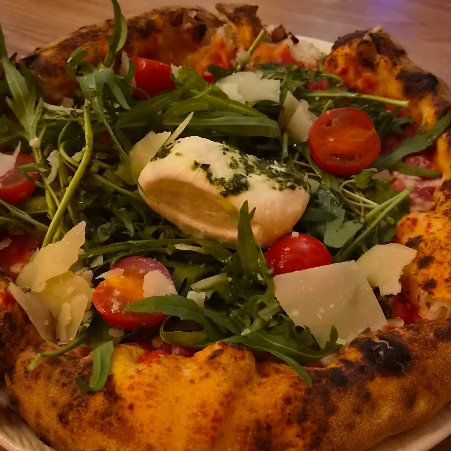 Close-up of the burrata pizza piled high with arugula