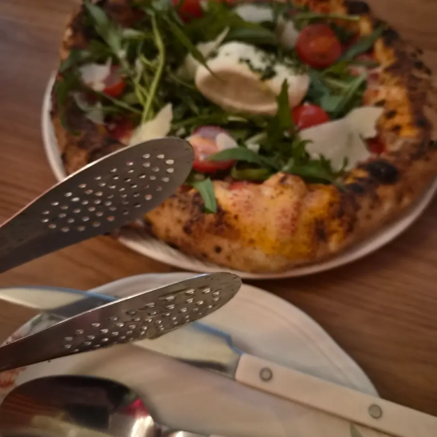 Tongs served alongside the pizza