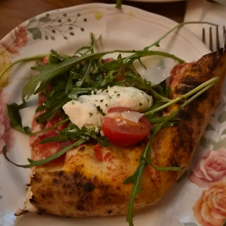 A slice of arugula burrata pizza served on a plate