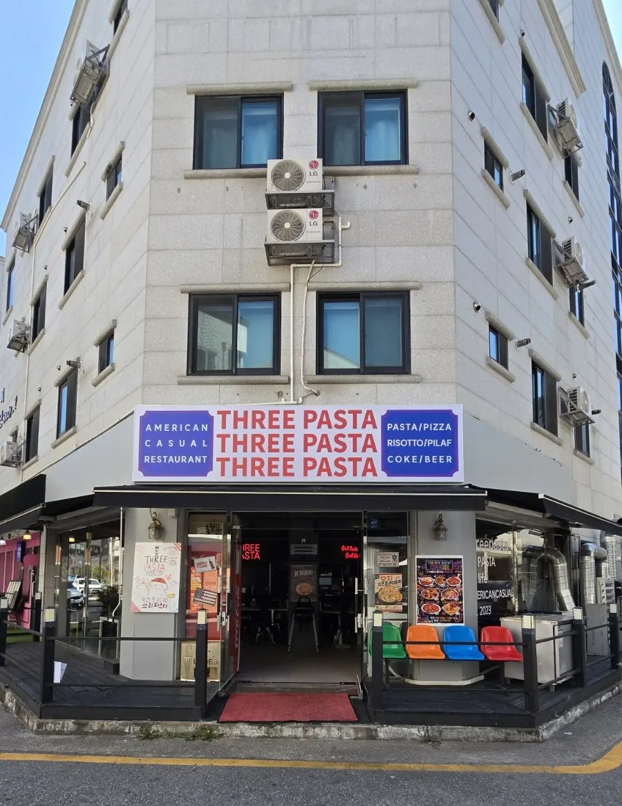 Exterior of Three Pasta with neon signage