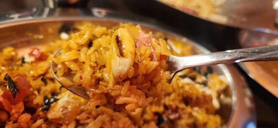 A spoonful of kimchi bacon pilaf with corn, bacon, and mushrooms