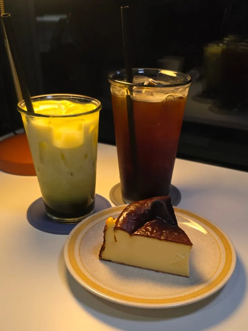 Stone-mill matcha latte, iced Americano, and Basque cheesecake on the table