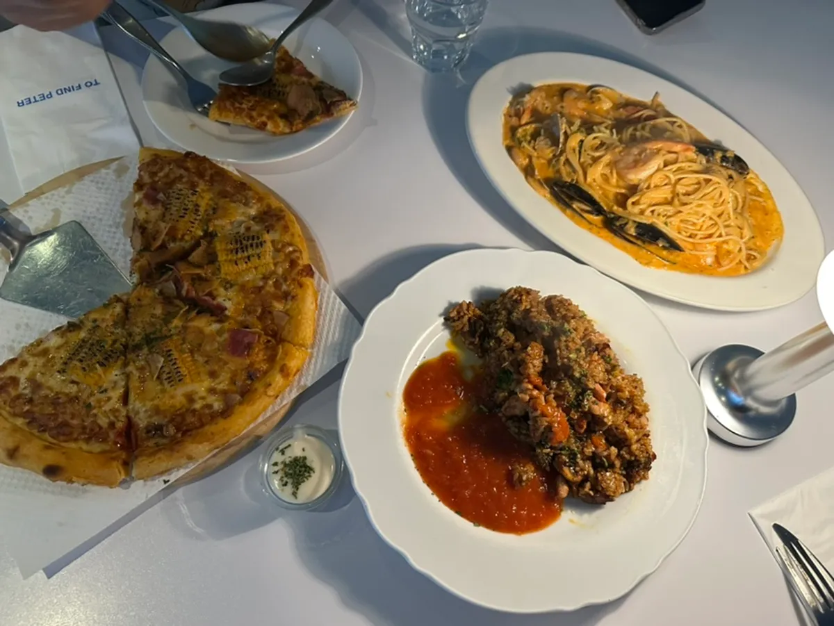 Table with pasta, pizza, and chicken pilaf all together